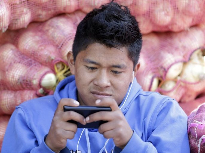 In this Aug. 24, 2014, photo, a young man texts a message on his mobile phone while working at the Mayorista Market in Quito, Ecuador. Ecuador's Central Bank is getting ready to use electronic currency in which consumers will initially be able to use it to make and receive payments using their cellphones. Ecuador is heralding its plans to create the world’s first government-issued digital currency, which some analysts believe could ultimately replace the country’s existing currency, the U.S. dollar, which the government cannot control. (AP Photo/Dolores Ochoa)