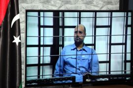 Journalists watch Saif al-Islam, the son of former Libyan leader Muammar Gaddafi, on a screen broadcasting his trial along with other Libyan officials under former Libyan leader Muammar Gaddafi attend their trial at a court in Tripoli, Libya, 22 June 2014. Two sons of former Libyan leader Gaddafi along with more than 30 Gaddafi-era officials were expected to appear in court, facing charges for crimes they allegedly committed while trying to stop the uprising that ousted Gaddafi. The 37 defendants face charges varying from murder, kidnapping, and embezzlement of public funds as well as abuses during the 2011 uprising that led to the ouster and killing of Gaddafi. EPA/SABRI ELMHEDWI