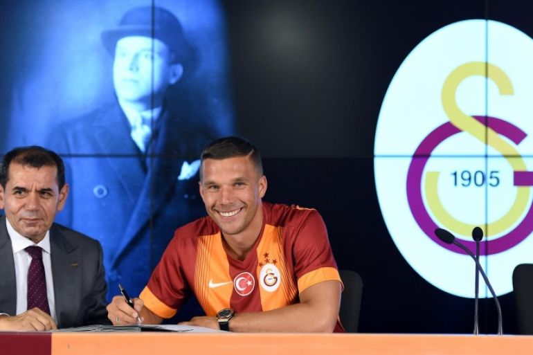 Galatasaray's new German forward Lukas Podolski (R) signs his new contract next to Galatasaray's president Dursun Ozbek (L) during a signing cerenomy on July 4, 2015 at the TT Arena stadium in Istanbul. Lukas Podolski signed a three year contract with Galatasary. AFP PHTO/ OZAN KOSE