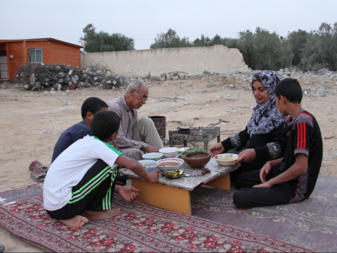 أسعد الشامي يستعد لتناول طعام الإفطار مع عائلته على أطلال منزله المدمر في غزة (الجزيرة)