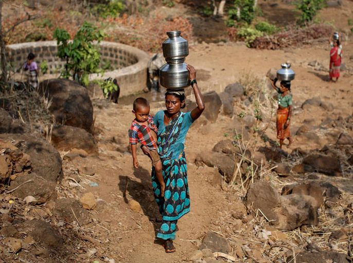 Shivarti, the second wife of Namdeo, holds her grandson while carrying metal pitchers filled with water from a well outside Denganmal village, Maharashtra, India, April 21, 2015. In Denganmal, a village in Maharashtra state, some men take a second or third wife just to make sure their households have enough drinking water. Becoming what are known as "water wives" allows the women, often widows or single mothers, to regain respect in conservative rural India by carrying water from the well quite some distance from the remote village. When the water wife, who does not usually share the marital bed, becomes too old to continue, the husband sometimes takes a third and younger spouse to fetch the water in metal pitchers or makeshift containers. REUTERS/Danish Siddiqui TPX IMAGES OF THE DAYPICTURE 22 OF 29 FOR WIDER IMAGE STORY "WATER WIVES OF MAHARASHTRA"  SEARCH "WATER WIVES" FOR ALL IMAGES TPX IMAGES OF THE DAY