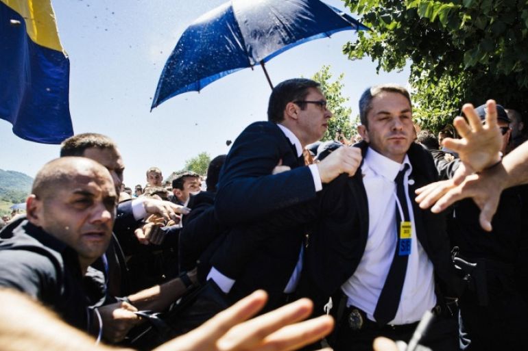 Bodyguards try to protect Serbian Prime Minister Aleksandar Vucic (C) from stones hurled at him by an angry crowd at the Potocari Memorial Center, near the eastern Bosnian town of Srebrenica on July 11, 2015. Tens of thousands of people gathered in Srebrenica on July 11 to commemorate the 20th anniversary of the massacre of thousands of Muslims in the worst mass killing in Europe since World War II. Serbian Prime Minister Aleksandar Vucic was forced to flee the Srebrenica memorial when the crowd started to chant 'Allahu Akbar' (God is Great) and to throw stones. AFP PHOTO / DIMITAR DILKOFF