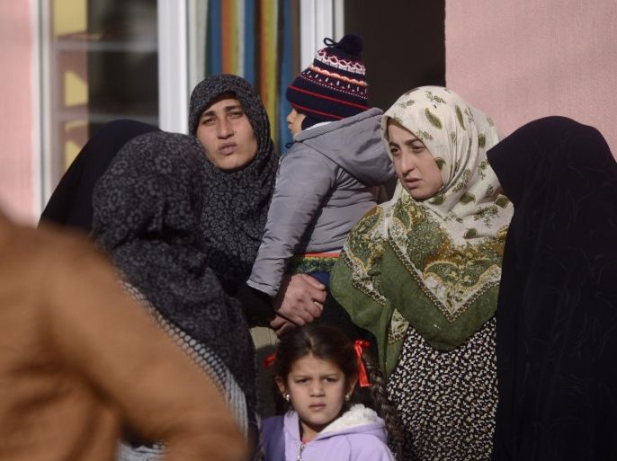 People gather during a police search of a house in the Roma suburb of the city of Pazardjik, South West Bulgaria on November 25, 2014. A Bulgarian Roma Muslim leader and members of his community are being investigated for terrorism and inciting war, the prosecution said after raiding a mosque in the southern town of Pazardzhik. According to media reports, the probe concerns pictures and videos posted on the social media Facebook that showed members of the tight-knit Roma Muslim neighbourhood posing in T-shirts and baseball caps with the symbols of the Islamic State group. AFP PHOTO / NIKOLAY DOYCHINOV