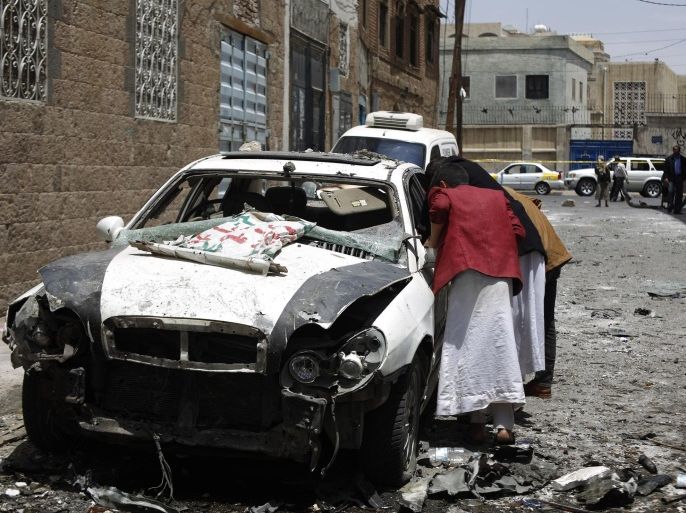 People look at the site of a car bomb attack in Sanaa, Yemen, Tuesday, June 30, 2015. The explosion occurred near a military hospital in the Yemeni capital on Monday, causing dozens of casualties including civilians, security officials said. The Islamic State's Sanaa Division claimed responsibility on Twitter for detonating the parked car bomb, according to the SITE Intelligence Group monitoring service. (AP Photo/Hani Mohammed)