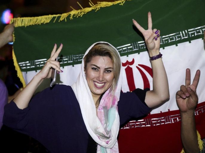 An Iranian woman shows the victory sign as people celebrate on a street following a landmark nuclear deal, in Tehran, Iran, Tuesday, July 14, 2015. Overcoming decades of hostility, Iran, the United States, and five other world powers struck a historic accord Tuesday to check Tehran's nuclear efforts short of building a bomb. The agreement could give Iran access to billions in frozen assets and oil revenue, stave off more U.S. military action in the Middle East and reshape the tumultuous region. (AP Photo/Ebrahim Noroozi)