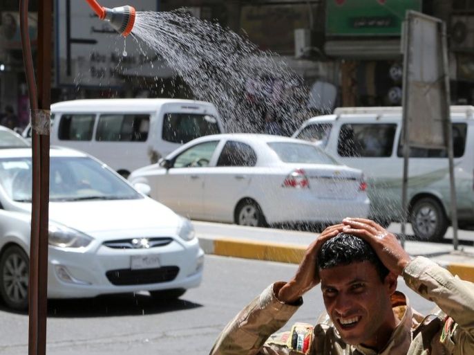 An Iraqi soldier cools off under a public shower to escape the summer heat during the holy, fasting month of Ramadan, when observant Muslims abstain from food or water during daylight hours, on a street in Baghdad, Iraq, Wednesday, June, 24, 2015. (AP Photo/Karim Kadim)