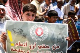 طفل يحمل لافتة أثناء الوقفة الاحتجاجية أمام مقر الأونروا في غزة وكالة الأناضول