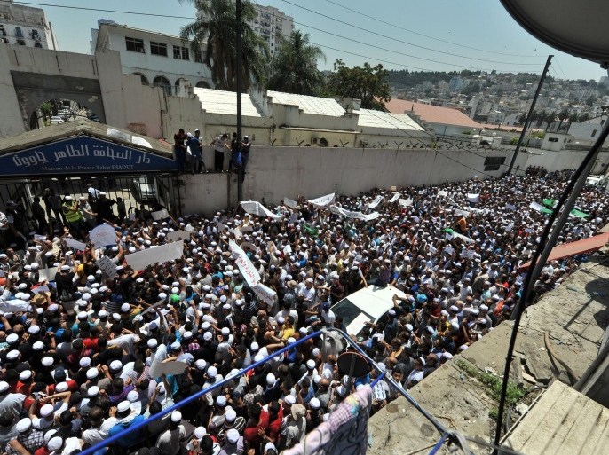 Hundreds of demonstrators of the Berber community stage a protest in front of a walled area where Algier's newspapers are headquartered in support of Berbers in the southern Ghardaia region where at least 22 people have died in ethnic unrest, in Algiers, Algeria, Wednesday, July 8, 2015. Authorities say ethnic clashes have left at least 22 people dead around Algeria's southern oasis city of Ghardaia, more than 600 kilometers (375 miles) south of Algiers, prompting the president to call an urgent security meeting. The Berbers and the Arabs in Ghardaia had for centuries lived together in harmony, but tensions started in late 2013 when a Berber shrine was vandalized. (AP Photo/Sidali Djarboub)