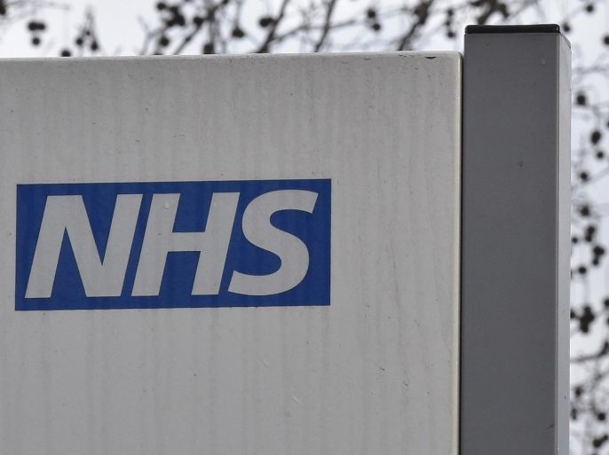 A National Health Service logo is seen on a hospital sign in front of the Big Ben clock tower of the Houses of Parliament, in central London January 6, 2015. It is likely that the National Health Service (NHS) will be a feature of the campaigning which has begun in earnest ahead of an unusually tight national election in four months' time with polls suggesting nobody will win a clear majority because of the rise of fringe parties. REUTERS/Toby Melville (BRITAIN - Tags: POLITICS HEALTH)