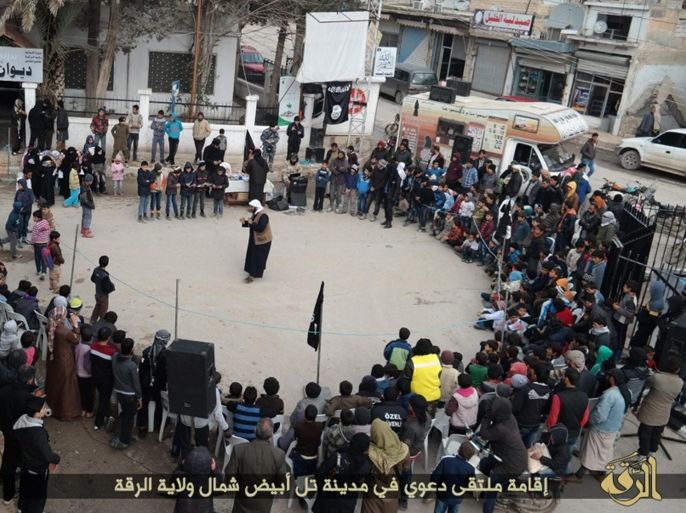 ADVANCE FOR USE SUNDAY, JULY 19, 2014 AT 1 P.M. EDT (17:00 GMT) AND THEREAFTER - In this photo released on Jan. 6, 2015, by a militant website, which has been verified and is consistent with other AP reporting, an Islamic State militant, center, speaks to youths during a street preaching event at Tel Abyad town in Raqqa province, northeast Syria. (Militant website via AP)