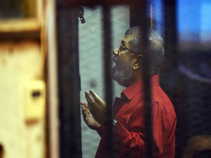Former Egyptian President, Mohamed Morsi, prays during the continuation of his trial for allegedly leaking classified documents to Qatar, Cairo, Egypt, 21 June 2015. The ousted President, along with ten others, has already been sentenced to death over a 2011 prison break, one of five charges laid against him, and has been sentenced to 20 years in jail for the killing of protesters outside the Presidential Palace in 2012.