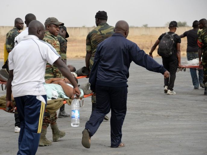 Cameroonian troops carry comrades who were wounded in fighting against Nigeria-based insurgent group Boko Haram before evacuating them to Yaounde from the airport in Maroua on February 18, 2015. Four African armies, from Nigeria, Cameroon, Chad and Niger, are currently directly engaged in the fight against Boko Haram. Regional forces have gone into action while awaiting the formation of a planned 8,700-strong, five-country force, whose make-up remains to be determined. AFP PHOTO / REINNIER KAZE