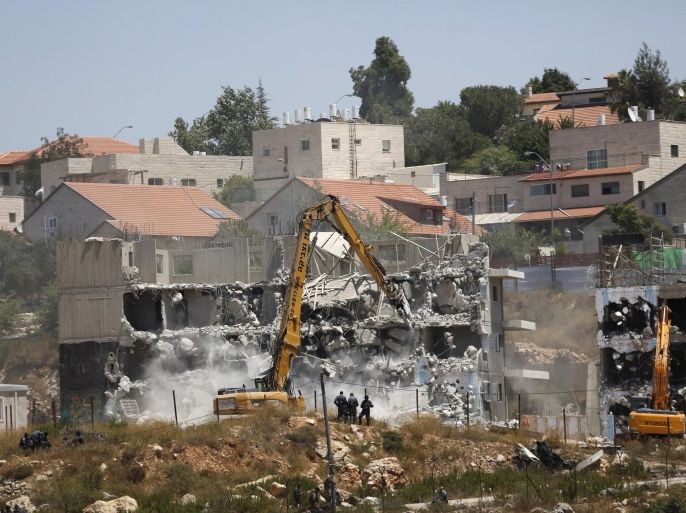 Israeli heavy machinery demolish vacant apartment blocs by order of Israel's high court, in the West Bank Jewish settlement of Beit El near Ramallah July 29, 2015. Israel gave final approval on Wednesday for plans to build 300 new homes in the Jewish settlement in the occupied West Bank, announcing the move as it carried out a court demolition order against two vacant apartment blocs at the site. Dozens of Jewish settlers have gathered over the past several days at Beit El settlement to protest against the demolition. Israel's Supreme Court ruled the two partially-built dwellings were constructed illegally on Palestinian-owned land. REUTERS/Mohamad Torokman