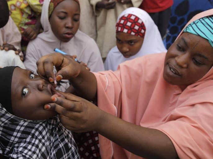 FILE- In this Sunday, April 13, 2014 file photo, an unidentified health official administers a polio vaccine to a child in Kawo Kano, Nigeria. Nigeria celebrates its first year with no reported case of polio on Friday, July 24, 2015 overcoming obstacles from Islamic supremacists who killed vaccinators to rumors the vaccine was a plot to sterilize Muslims. Just 20 years ago this West African nation was recording 1,000 cases a year of the crippling disease _ the highest number in the world _ and was stigmatized as the polio-epicenter of the world. (AP Photo/ Sunday Alamba, File)