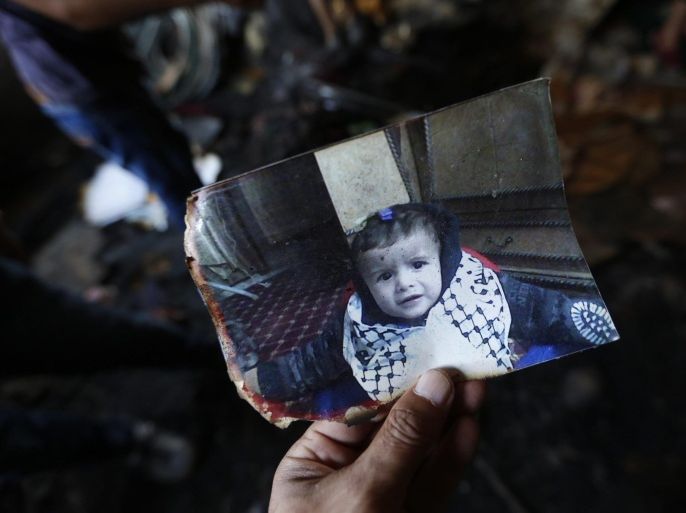 A photograph of 18-month-old Ali Dawabsha in the fire damage home in the West Bank village of Douma near Nablus City, 31 July 2015. The Palestinian infant was killed and several people injured when their home was set alight in the northern West Bank early 31 July 2015, an official said. A group of masked people believed to be Israeli settlers threw flammable bombs into two houses on the outskirts of the village of Doma, south of Nablus, said Ghassan Daghlas, a Palestinian Authority official.