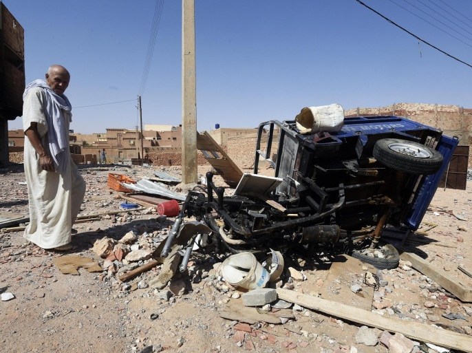 A man from the Arab community walks past the wreckage of a vehicle on July 9, 2015, following clashes between Berbers and Arabs in the Algerian town of Guerara in the M'zab valley. Algeria is mobilising the army after 22 people were killed in the worst ethnic clashes between Berbers and Arabs in years, as more details emerged of the violence. AFP PHOTO / FAROUK BATICHE