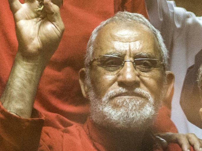 Egyptian Muslim Brotherhood leader Mohamed Badie (C) flashes the four finger symbol known as 'Rabaa' from behind the defendant's cage as the judge reads out the verdict sentencing him and more than 100 other defendants on May 16, 2015 at the police academy in Cairo. An Egyptian court sentenced deposed Islamist president Mohamed Morsi to death for his role in a mass jailbreak during the 2011 uprising and issued the same sentence to more than 100 other defendants including Badie and his deputy Khairat al-Shater. AFP PHOTO / KHALED DESOUKI