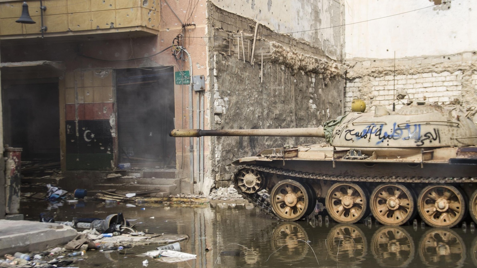 ‪إحدى الدبابات تتمركز فوق بركة مياه وبين البنايات شبه المدمرة في أحد شوارع بنغازي‬ (رويترز)