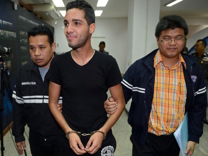 Hamza Bendelladj of Algeria (C), a suspect on the US Federal Bureau of Investigation's top ten wanted list for allegedly hacking private accounts in 217 banks and financial companies worldwide, is escorted by Thai police officers during a press conference at the Immigration Police Bureau in Bangkok on January 7, 2013. Bendelladj, who graduated in computer sciences from a college in Algeria in 2008, has allegedly hacked private accounts in 217 banks and financial companies worldwide, amassing 'huge amounts' in illicit earnings, the police commissioner told a press conference.
