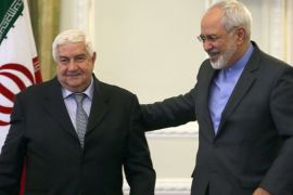 Iranian Foreign Minister Mohammad Javad Zarif (R) escorts his Syrian counterpart Walid Muallem off the podium after a press conference in Tehran on December 8, 2014, ahead of a conference with their Iraqi counterpart on combating extremism. Iran is the main regional ally of Syrian President Bashar al-Assad, and Tehran has acknowledged sending military advisers to assist his forces in their fight against armed rebels and jihadist militants. AFP PHOTO/ ATTA KENARE