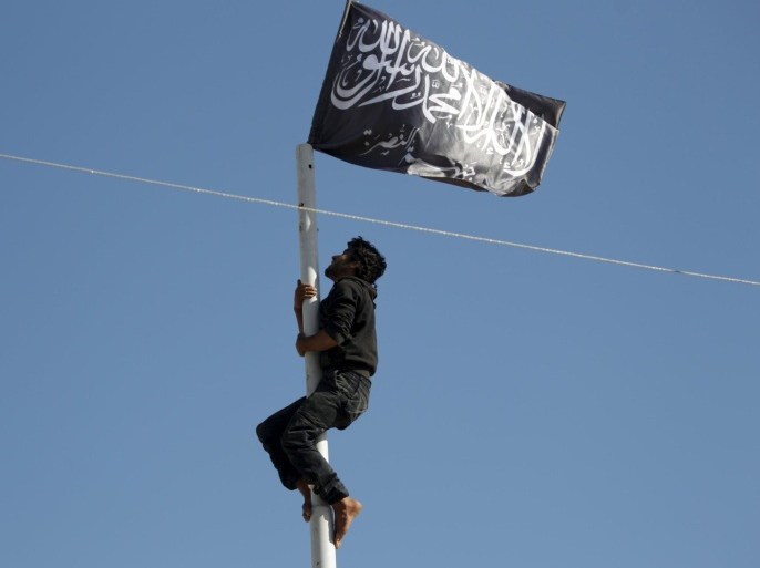 A member of al Qaeda's Nusra Front climbs a pole where a Nusra flag was raised at a central square in the northwestern city of Ariha, after a coalition of insurgent groups seized the area in Idlib province May 29, 2015. A Syrian insurgent alliance which has captured the last government-held town in the northwestern Idlib province made further advances on Friday, a monitoring group and fighters said. REUTERS/Khalil Ashawi