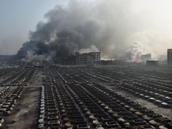 TOPSHOTSSmoke billows behind rows of burnt out cars at the site of a series of explosions in Tianjin, northern China on August 13, 2015. A series of massive explosions at a warehouse in the northern Chinese port city of Tianjin killed 17 people, state media reported August 13, as witnesses described a fireball from the blasts ripping through the night sky. AFP PHOTO / GREG BAKER