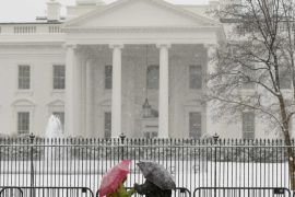 A couple stands in front of the White House as snow falls in Washington March 5, 2015. Federal offices were closed today due to the predicted snowfall of up to 7 inches in the nation's capital. A large winter storm reaching from Texas to southern New England had dumped over a foot (30 cm) of snow on parts of the eastern United States by early Thursday morning. REUTERS/Kevin Lamarque (UNITED STATES - Tags: ENVIRONMENT SOCIETY)