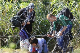 Syrian migrant family cross under a fence as they enter Hungary at the border with Serbia, near Roszke, August 28, 2015. REUTERS/Bernadett Szabo