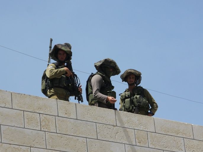جنود إسرائيليون يعتلون سطح أحد المنازل الفلسطينية بمدينة الخليل بالضفة الغربية المحتلة