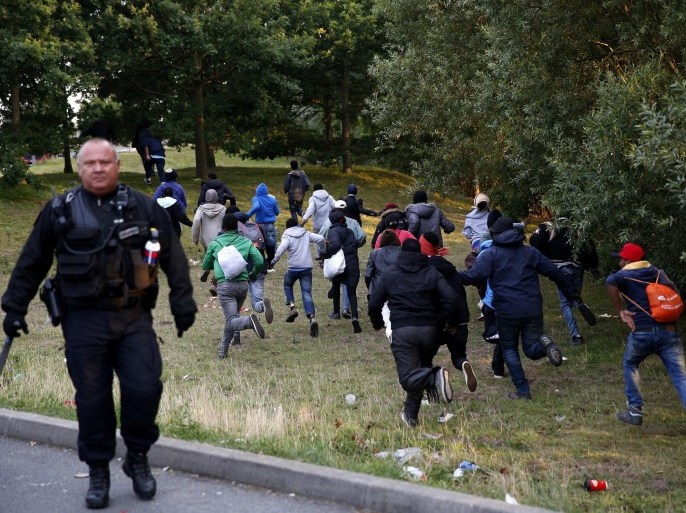 Migrants escape from the French Police as they try to catch a train to reach England, in Calais, France, 30 July 2015. A Sudanese man, between 25 and 30 years old, was crushed under a truck as up to 1,500 migrants tried to force their way into the tunnel, which links France and Britain under the English Channel. Since the beginning of the year there were more than 37,000 interceptions of migrants in Calais attempting to cross to England, the Eurotunnel operators said on 29 July.