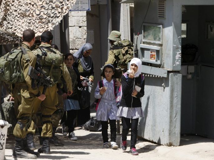 Palestinian schoolgirls cross an Israeli checkpoint as they return from school to their homes, on the first day of a new school year in the West Bank city of Hebron August 24, 2015. REUTERS/Mussa Qawasma