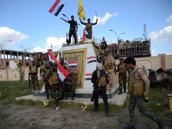 Shiite fighters from the Popular Mobilisation units celebrate in front of the the provincial council building inside the northern Iraqi city of Tikrit on March 31, 2015 during a military operation to retake it from the Islamic State (IS) group. Prime Minister Haider al-Abadi Prime Minister said security and allied forces backed by US-led coalition aircraft 'liberated' Tikrit, 80 miles (130 kilometers) north of Baghdad, the country's biggest victory yet in the fight against IS jihadists. AFP PHOTO / STR