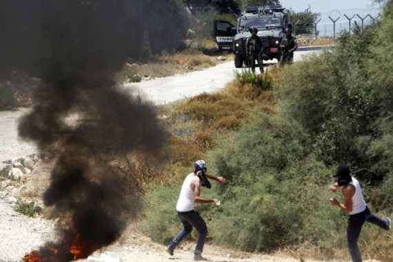Palestinians hurl stones towards Israeli border police officers during a demonstration against the separation barrier, in the West Bank village of Beit Jallah, near Jerusalem, Sunday, Aug. 23, 2015. (AP Photo/Mahmoud Illean)