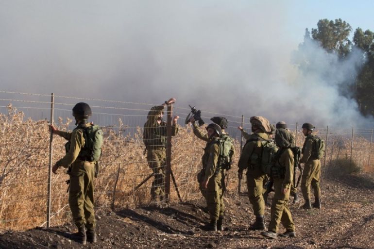 Israeli soldiers stand next to smoke from a fire caused by a rocket attack in northern Israel, near the Lebanese border, August 20, 2015. Rockets that struck an northern Israeli village near the Lebanese border on Thursday, causing no casualties, were launched from the Syrian Golan Heights, the Israeli army said. REUTERS/JINIPIX ISRAEL OUT