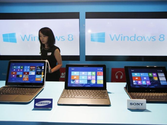 FILE - In this Friday, Oct. 26, 2012, file photo, a woman walks past laptop computers running Microsoft Windows 8 operating system during its launching ceremony in Hong Kong. Worldwide shipments of personal computers fell during the third quarter of 2013. It is the sixth straight quarter of decline as cheaper tablet computers and smartphones cut into demand, according to market research firms IDC and Gartner Inc. (AP Photo/Kin Cheung, File)