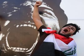 A man chants anti corruption slogans in support of Iraqi Prime Minister Haider al-Abadi, with a national flag around his neck, during a demonstration in Tahrir Square in Baghdad, Iraq, Friday, Aug. 14, 2015. Thousands of people demonstrated in cities across Iraq on Friday to show support for a reform plan put forth by the prime minister this week while still demanding that greater measures be taken to target corruption and restore basic services. (AP Photo/Karim Kadim)
