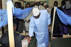 Mali's President Ibrahim Boubacar Keita (C) holds a medal next to a patient's bed in a clinic in Kati, near Bamako, on August 6, 2015, as he visits soldiers injured in an attack on their camp in northern Mali on August 3, which left 11 soldiers dead. Malian forces on August 5 arrested five people suspected of involvement in an attack that left 11 soldiers dead, but the release of a former top jihadist sparked outrage among human rights groups. AFP PHOTO / HABIBOU KOUYATE