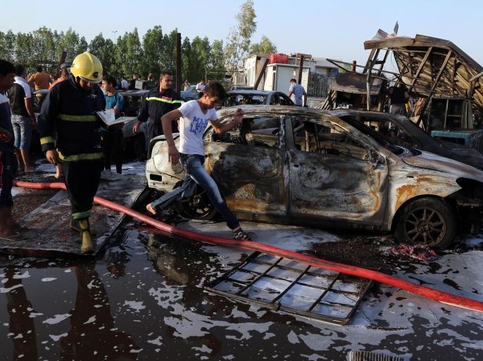 Civilians and security forces gather at the scene of a deadly car bomb in the Habibiya neighborhood of Sadr City, Baghdad, Iraq, Saturday, Aug. 15, 2015. An Iraqi police official says the explosion at a popular car dealership in eastern Baghdad, that has been targeted multiple times in the past, has killed at least eight and wounded over a dozen people. (AP Photo/Karim Kadim)