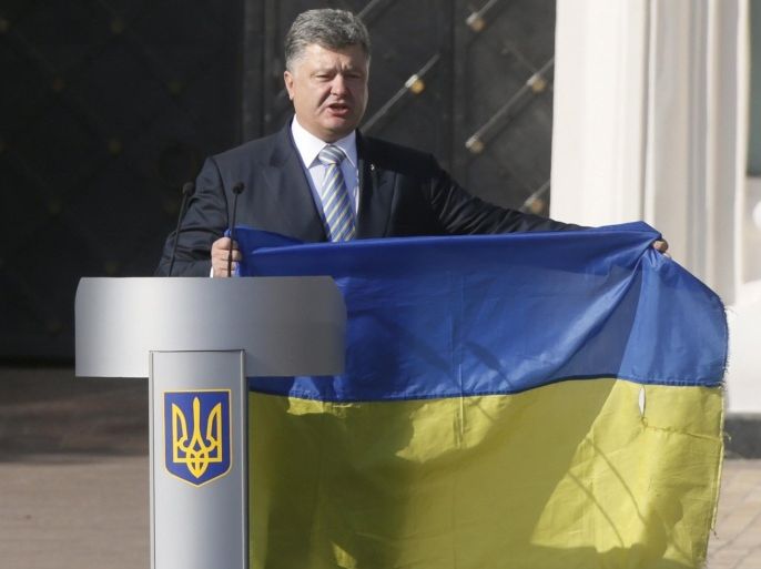 Ukraine's President Petro Poroshenko delivers a speech, while holding a flag brought from eastern regions of the country where a military conflict takes place, during a ceremony marking the Day of the State Flag, on the eve of the Independence Day, in Kiev, Ukraine, August 23, 2015. REUTERS/Valentyn Ogirenko