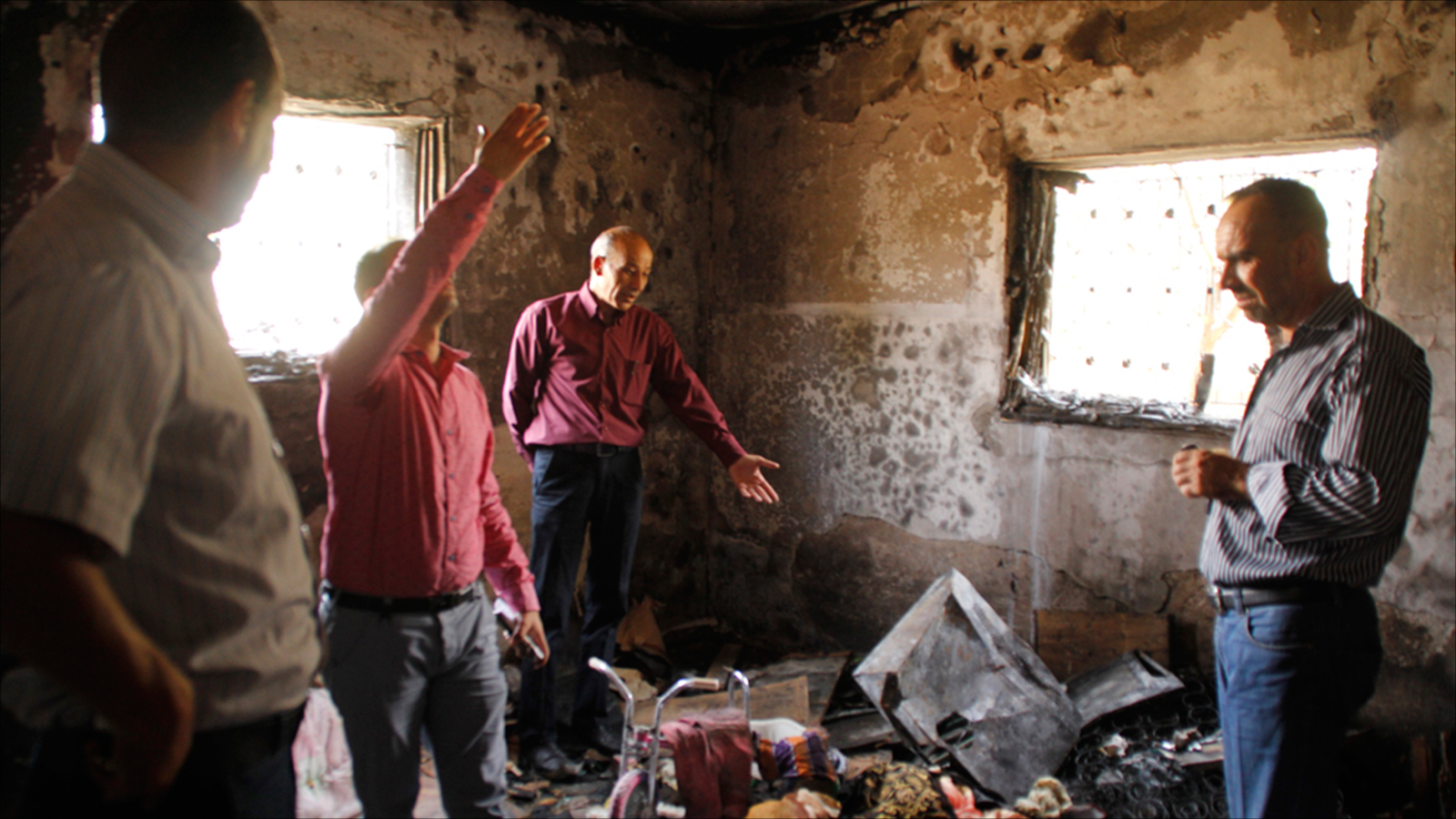 مواطنون يتفقدون ما حل بمنزل عائلة سعد دوابشة الذي أحرقه المستوطنون في قرية دوما جنوب نابلس (الجزيرة نت)