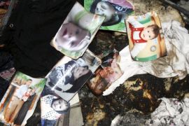 A picture of 18-month-old Palestinian baby Ali Dawabsheh (top L), who was killed after his family's house was set to fire in a suspected attack by Jewish extremists, is seen with other pictures of his family as they are collected by a relative at the burnt house in Duma village near the West Bank city of Nablus July 31, 2015. Suspected Jewish extremists set fire to a Palestinian home in the occupied West Bank on Friday, killing Dawabsheh and seriously injuring several other family members, an act that Israel's prime minister described as terrorism. REUTERS/Abed Omar Qusini