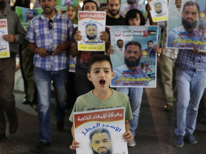 Palestinian protesters take part in a rally in the West Bank city of Ramallah on August 19, 2015, in solidarity with Mohammed Allan (portraits), a Palestinian detainee held without charge in an Israeli jail since November and whose two-month hunger strike has put his life at risk. Israel's High Court suspended the detention-without-trial order on hunger-striking Palestinian prisoner Allan but said he must remain in hospital pending a decision on his future. AFP PHOTO / ABBAS MOMANI