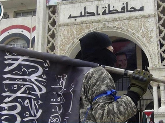 مقاتل يحمل علم جبهة النصرة أمام مبنى محافظة إدلب يوم 25 مارس/ آذار الماضي (أسوشيتد برس)
