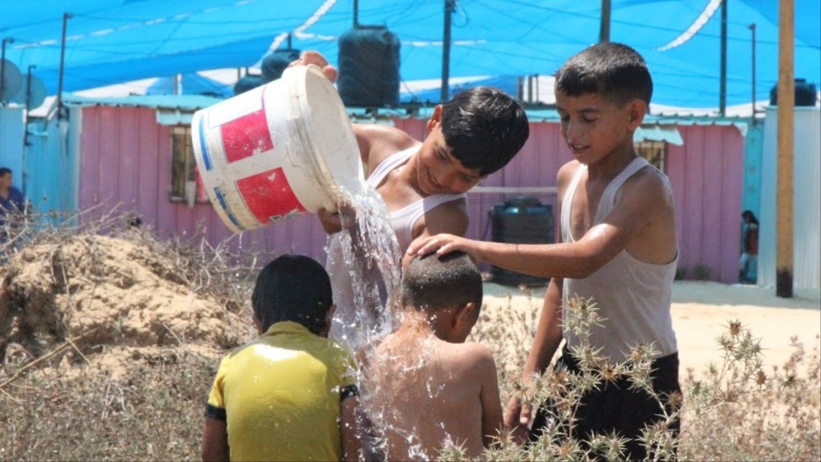 الصغار يسكبون المياه على أجسادهم لتخفيف مضاعفات الحر (الجزيرة نت)