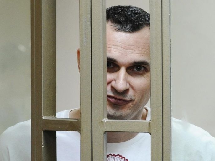 Oleg Sentsov reacts as the verdict is delivered as he stands behind bars at a court in Rostov-on-Don, Russia, Tuesday, Aug. 25, 2015. A court in the southern city of Rostov-on-Don convicted Sentsov, a prominent Ukrainian filmmaker, of conspiring to commit terror attacks and sentenced him to 20 years in prison in what critics called a politically motivated show trial. (AP Photo)