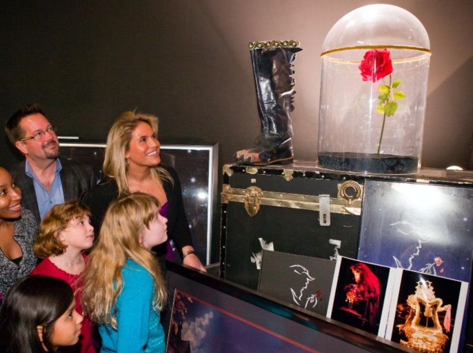 In this undated image released by Disney Theatrical Productions, visitors look at the enchanted rose from the Disney musical “Beauty and the Beast” while on the Disney on Broadway: Behind the Magic walking tour. The tour is the only one that lets visitors handle props from Broadway shows in a Broadway theater. (Disney Theatrical Productions via AP)