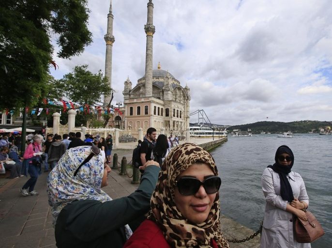 Tourists take pictures at the Ortakoy square in Istanbul, Turkey, backdropped by the Ottoman-era Mecidiye mosque and the Bosporus Bridge, Sunday, June 7, 2015. Turkey is heading to the polls on Sunday in a crucial parliamentary election that will determine whether ruling party lawmakers can rewrite the constitution to bolster the powers of Erdogan. (AP Photo/Lefteris Pitarakis)
