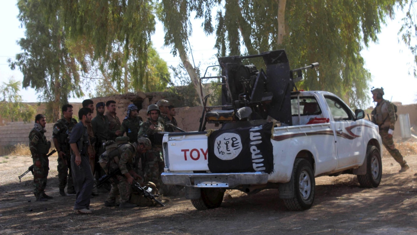 أفراد من البشمركة بجوار عربة تابعة لتنظيم الدولة جنوب بلدة داقوق أمس الأربعاء (رويترز)