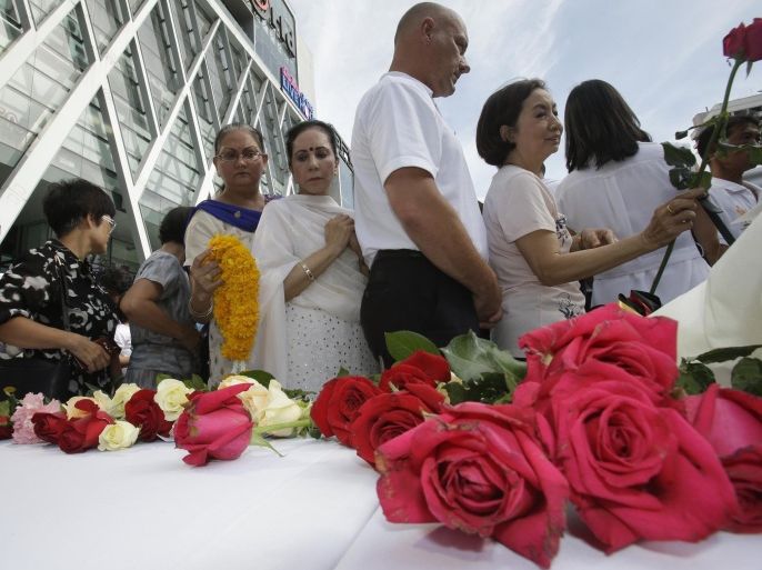People gather at a shopping plaza across from the Erawan Shrine at Rajprasong intersection, the scene of Monday's bombing, for a multi-denominational religious service for victims in Bangkok, Thailand, Friday, Aug. 21, 2015. Religious ceremonies were held to honor the victims of the deadly bombing at a Bangkok shrine four days ago. (AP Photo/Sakchai Lalit)