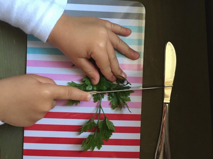 Cropped Image Of Person Chopping Coriander In Kitchen